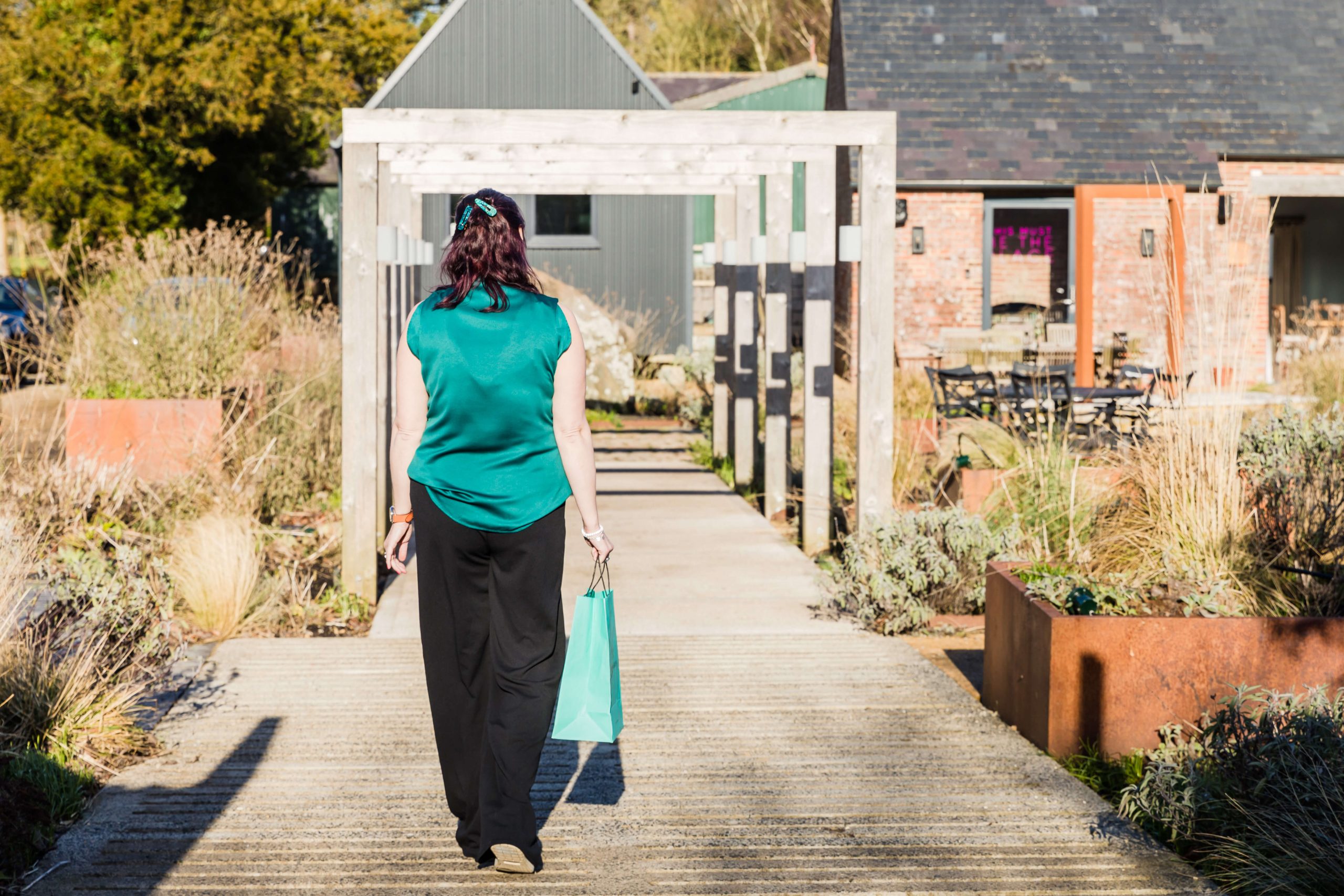 Melissa at Bee Time Clever walking on some decking with a shopping bag in her hand